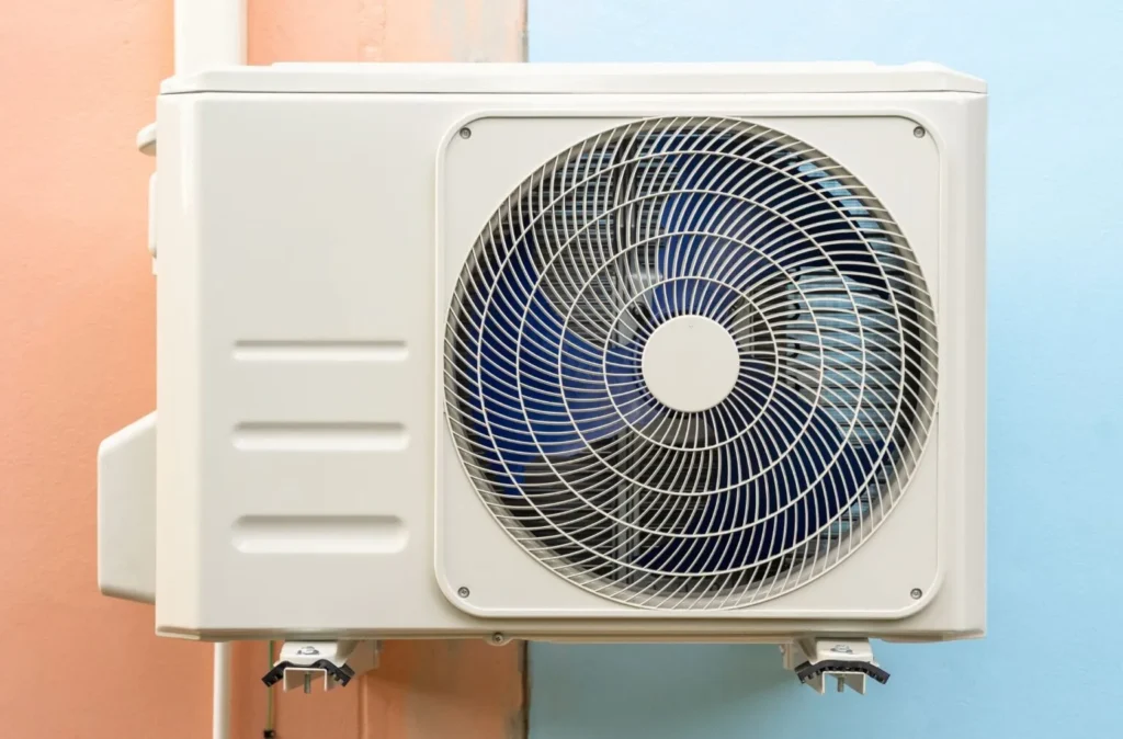 A Outdoor unit of an air conditioner mounted on a wall with pastel colors.